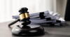 a gavel in front of a stack of documents sitting on a wooden table 